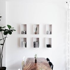 a dining room table with chairs and bookshelves on the wall