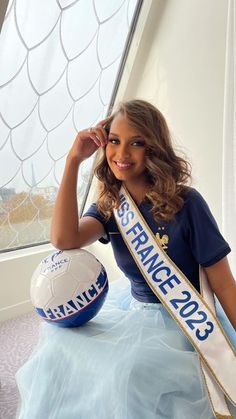 a woman sitting next to a soccer ball on top of a blue and white floor