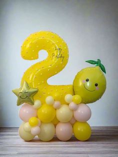 a yellow balloon shaped like a number two with stars on the top and balloons around it