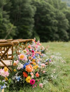 a row of wooden benches sitting on top of a lush green field covered in flowers