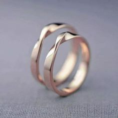 two wedding bands are shown on top of each other, with one ring in the middle