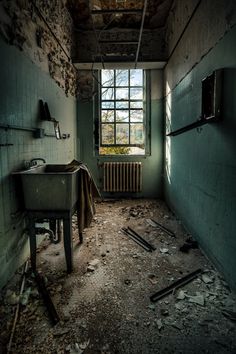 an old run down bathroom with a sink and window