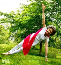 an older woman is doing yoga in the grass with her hands up and legs spread out