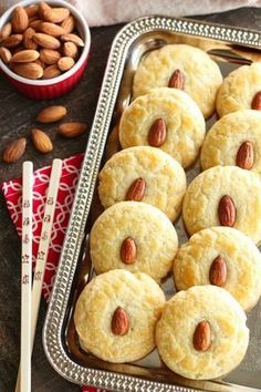 almond cookies are arranged on a metal tray next to some nuts and a red napkin