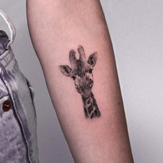 a small giraffe tattoo on the arm