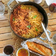 a pan filled with spaghetti and meat on top of a wooden table