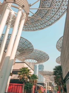 an outdoor area with many white columns and palm trees in the foreground, surrounded by tall buildings