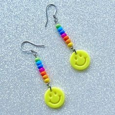 a pair of yellow smiley face earrings with rainbow beads