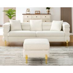 a living room with a white couch and footstool in front of a dresser