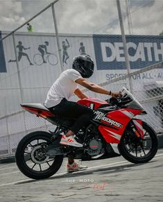 a man riding on the back of a red motorcycle