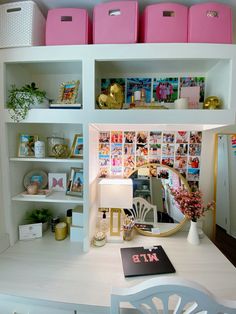 a white desk topped with pink bins filled with books and other items on top of it