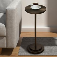 a table with a cup of coffee on it in front of a couch and rug