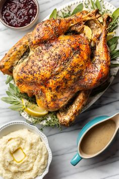 a roasted chicken on a platter with mashed potatoes and garnishes