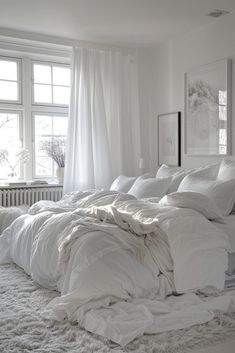 an unmade bed with white sheets and pillows in a bedroom next to a window