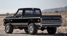 a black pickup truck parked on top of a dirt field