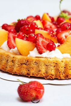 a cake with fruit and whipped cream on top is sitting next to a strawberries