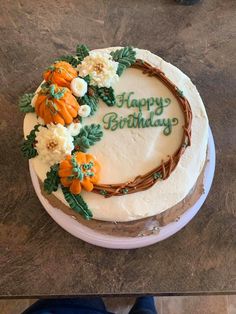 a birthday cake decorated with flowers and leaves