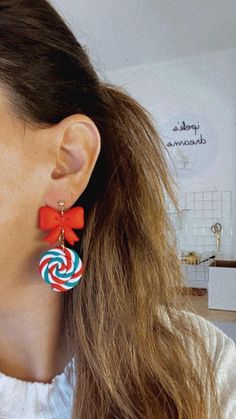 a woman wearing red, white and blue earrings with candy canes hanging from them