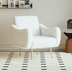 a white chair sitting on top of a rug next to a wall with pictures on it