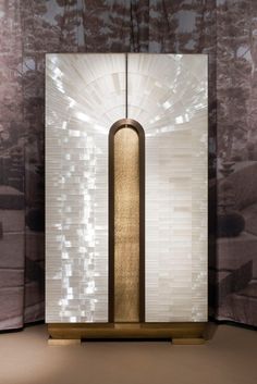 a tall white and gold object in front of a curtained window with light coming through it