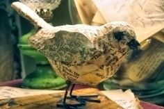 a small bird sitting on top of a table next to some papers and other items