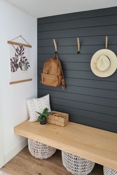 a wooden bench sitting next to a wall with hooks on it's sides and two hats hanging from the hooks