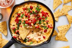 tortilla dip in a cast iron skillet topped with tomatoes, cheese and cilantro