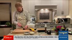 a man standing in a kitchen preparing food on top of a wooden cutting board next to a counter