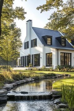 a large white house sitting next to a small pond in front of it's windows