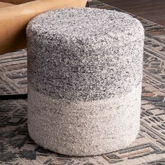 a grey and white ottoman sitting on top of a rug