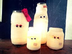 four mason jars with faces and eyes are sitting on a table