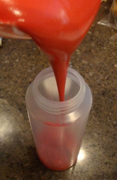 a person pouring red liquid into a cup