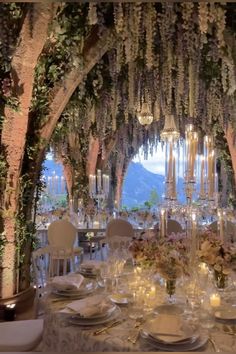 a table set up for a formal dinner with candles and flowers on the tables in front of it