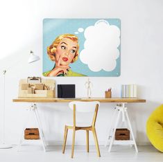 a desk with a chair and a painting on the wall above it that has a woman's face in thought bubble