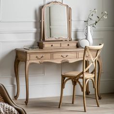 a wooden desk with a mirror and chair next to it in a white walled room