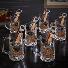 six clear mugs filled with different types of wine and cigars are sitting on a table