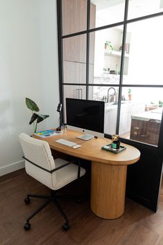 a desk with a monitor, keyboard and mouse on it in front of a window