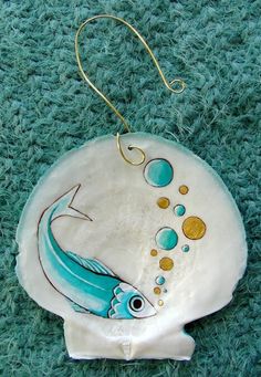 a ceramic ornament with a blue fish on it's side and bubbles in the water