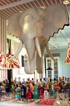 an elephant head hanging from the ceiling above a bar filled with liquor bottles and glasses