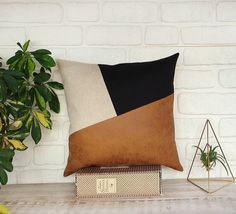 a brown and black pillow sitting on top of a wooden table next to a potted plant