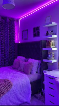 a bedroom with purple lighting in the ceiling and bed covered in fluffy blankets on it