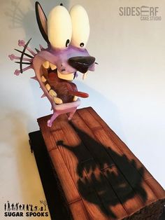 a figurine that is sitting on top of a piece of wood with its mouth open