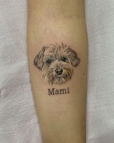 a small dog is on the leg of a person with a name tattooed to it