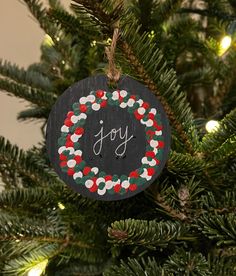 a christmas ornament hanging on a tree with the word joy painted on it