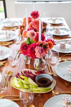 the table is set with plates, silverware and flowers