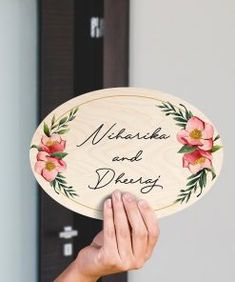 a person holding up a wooden sign with flowers on it