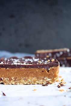 two pieces of chocolate and coconut bar sitting on top of a white tablecloth covered with powdered sugar