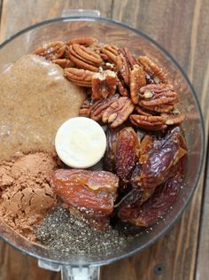 a food processor filled with nuts, chocolate and pecans on top of a wooden table