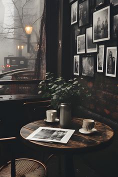 a table with two cups on it in front of a window filled with framed pictures