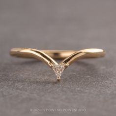 a yellow gold ring with a triangle shaped diamond on the top, sitting on a gray surface